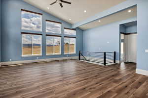 Family room featuring dark wood-type flooring, recessed lighting, ceiling fan, high vaulted ceiling, and natural light. These are the wide stairs that lead to the basement area.