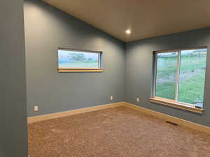 Spare room with carpet floors and vaulted ceiling