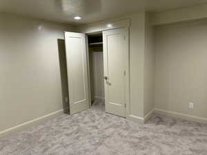 Unfurnished bedroom featuring light carpet and a closet