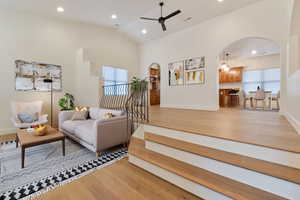 Living room featuring wood-type flooring, ceiling fan, and lofted ceiling. Virtually staged