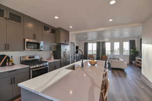 Pics are of model home.Kitchen with gray cabinetry, a kitchen island with sink, sink, and appliances with stainless steel finishes