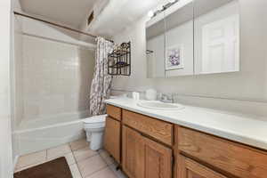 Full bathroom with tile patterned flooring, shower / bath combo, vanity, and toilet