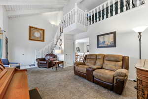 Carpeted living room with beam ceiling, high vaulted ceiling, ceiling fan, and wooden ceiling