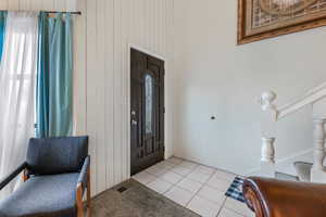 Tiled foyer featuring wooden walls