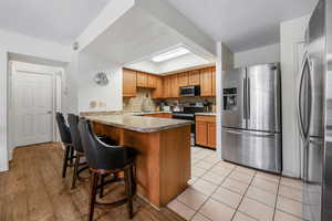 Kitchen featuring kitchen peninsula, appliances with stainless steel finishes, backsplash, a breakfast bar, and sink