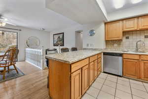 Kitchen featuring sink, stainless steel dishwasher, decorative backsplash, ceiling fan, and kitchen peninsula