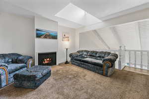 Living room featuring beam ceiling, a skylight, and light carpet