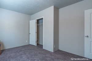 Unfurnished bedroom featuring carpet flooring, a closet, and a textured ceiling