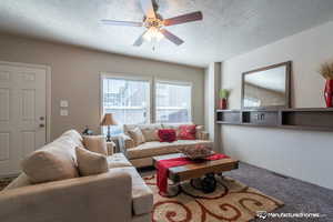 Living room featuring carpet flooring, ceiling fan, and a textured ceiling