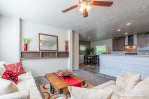 Living room featuring ceiling fan and a textured ceiling