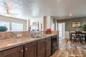 Kitchen featuring dark brown cabinets, a textured ceiling, sink, black dishwasher, and dark hardwood / wood-style floors