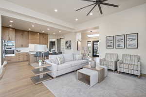 Living room featuring a barn door, ceiling fan, sink, and light hardwood / wood-style floors