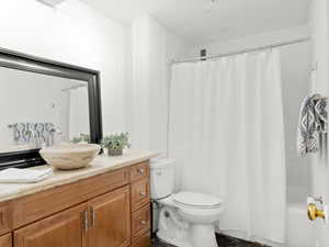 Full bathroom with vanity, toilet, and shower / bath combo with shower curtain