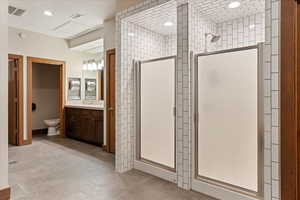 Bathroom featuring vanity, a shower with shower door, and toilet