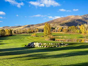 Surrounding community with a mountain view and a lawn