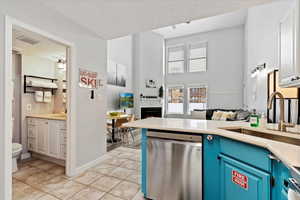 Kitchen featuring dishwasher, blue cabinets, sink, light tile patterned floors, and a textured ceiling