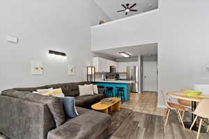 Living room featuring ceiling fan, light hardwood / wood-style floors, and a high ceiling