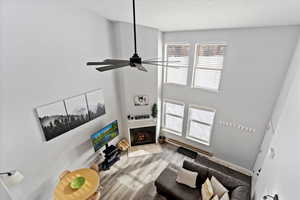 Living room with ceiling fan, light hardwood / wood-style floors, a towering ceiling, and a baseboard radiator