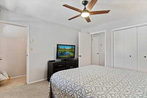 Bedroom with a closet, light colored carpet, and ceiling fan