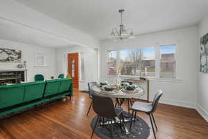 Dining area featuring wood-type flooring, a tile fireplace, a textured ceiling, and a notable chandelier