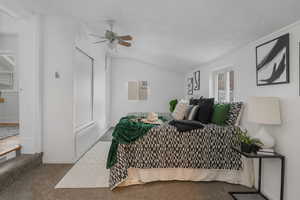 Bedroom with lofted ceiling, carpet flooring, a textured ceiling, and ceiling fan