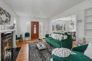 Living room featuring a fireplace, a textured ceiling, hardwood / wood-style flooring, built in shelves, and an inviting chandelier