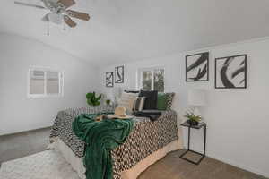 Carpeted bedroom with ceiling fan, a textured ceiling, and lofted ceiling