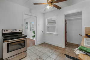 Kitchen featuring ceiling fan, sink, light tile patterned floors, and stainless steel range with electric stovetop