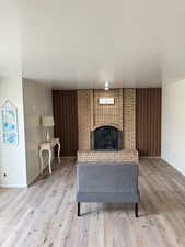 Living area featuring light wood-style floors, baseboards, and a brick fireplace