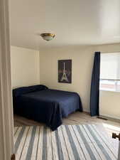 Bedroom with wood finished floors, baseboards, and visible vents