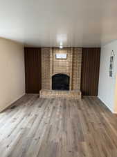 Unfurnished living room featuring a brick fireplace and light hardwood / wood-style flooring