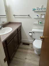 Bathroom with wood-type flooring, toilet, and vanity