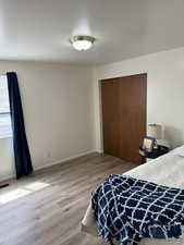 Bedroom featuring light wood finished floors, visible vents, a closet, and baseboards
