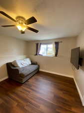 Unfurnished living room with a textured ceiling, dark hardwood / wood-style floors, and ceiling fan