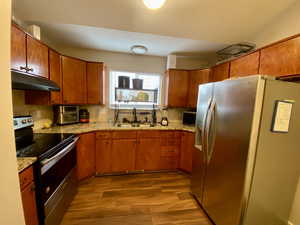 Kitchen with decorative backsplash, hardwood / wood-style flooring, sink, and appliances with stainless steel finishes