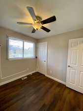 Unfurnished bedroom featuring ceiling fan and dark hardwood / wood-style floors