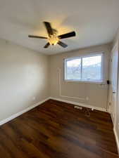 Unfurnished room featuring ceiling fan and dark wood-type flooring