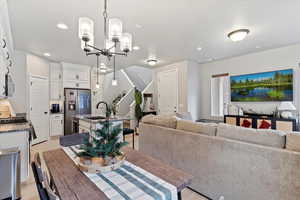 Dining space with light hardwood / wood-style flooring, an inviting chandelier, and sink