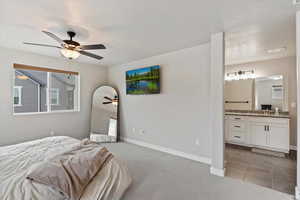 Tiled bedroom featuring connected bathroom, ceiling fan, and sink