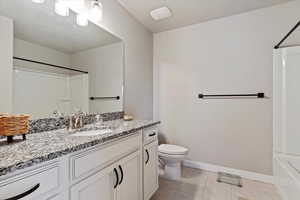 Full bath with tile patterned floors, toilet, shower / tub combination, vanity, and baseboards