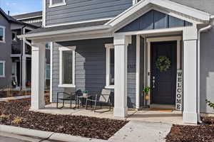 View of exterior entry with a porch and a shingled roof
