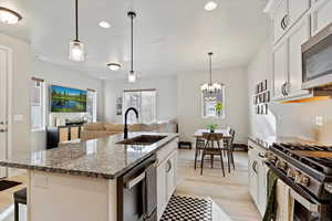 Kitchen featuring white cabinetry, a sink, appliances with stainless steel finishes, open floor plan, and recessed lighting