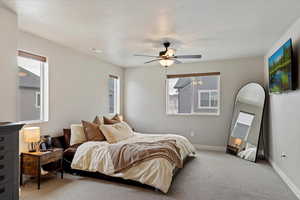 Bedroom with multiple windows, a textured ceiling, light colored carpet, and ceiling fan