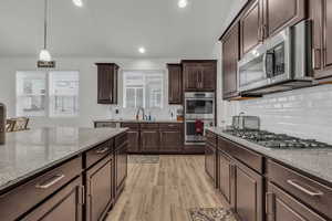 Kitchen with double ovens, decorative light fixtures, stainless steel appliances, and backsplash