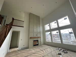 Unfurnished living room featuring a large fireplace and a high ceiling