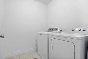 Washroom featuring light tile patterned floors and washer and clothes dryer