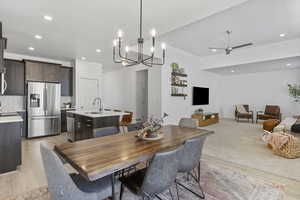 Dining space with sink, ceiling fan with notable chandelier, and light hardwood / wood-style flooring