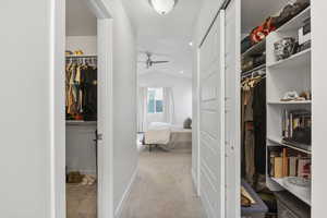 Spacious closet with light carpet, ceiling fan, and lofted ceiling