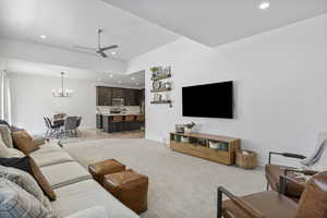 Carpeted living room with ceiling fan with notable chandelier