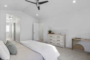 Bedroom featuring light carpet, ensuite bath, ceiling fan, and lofted ceiling